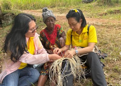 Two women learning to make a basket with one local woman